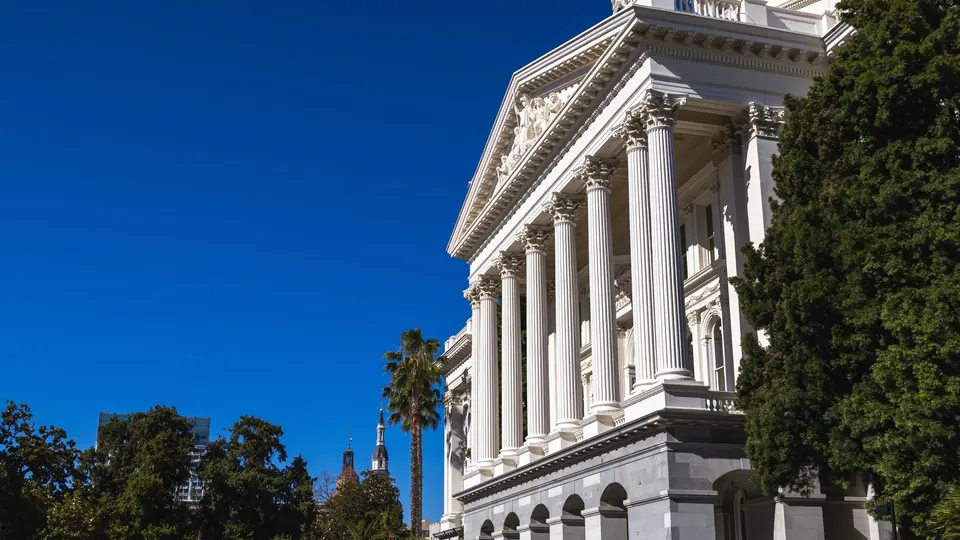White columns of the California State Capitol in Sacramento under a blue sky