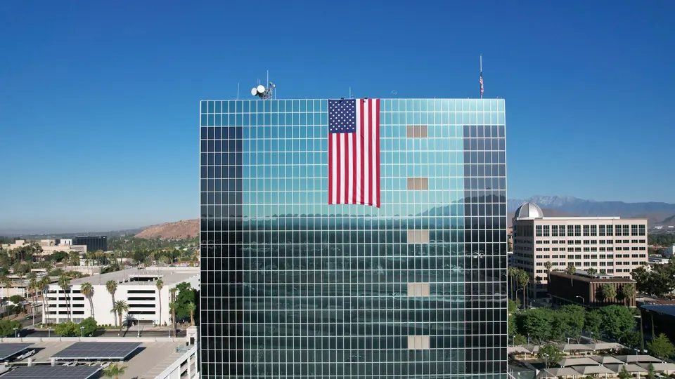 A glass county administration building with a large American flag in Southern California