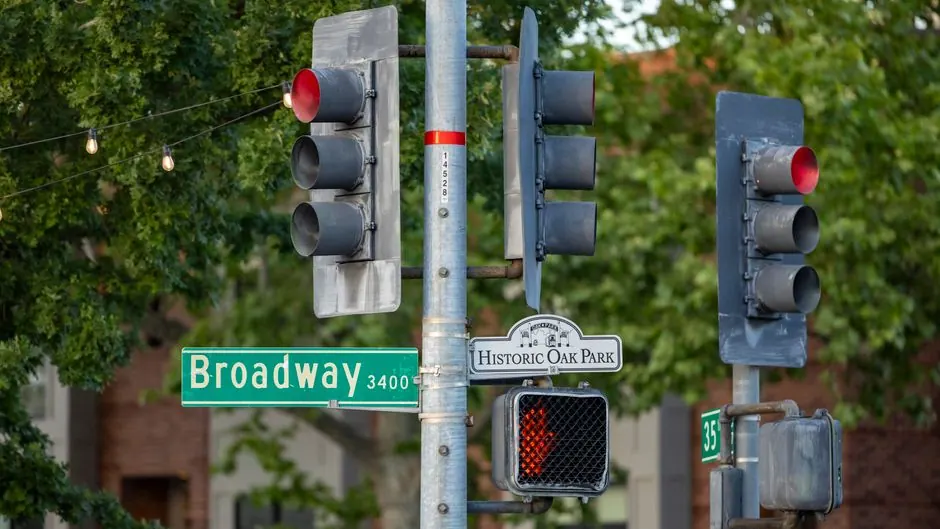 Traffic signals showing red at a city intersection with a street sign